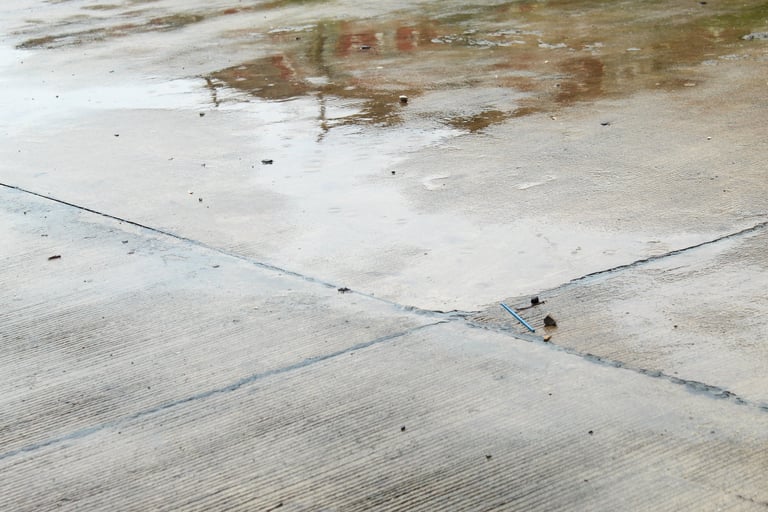Wet outdoor concrete surface after rain showing water absorption into porous unsealed concrete