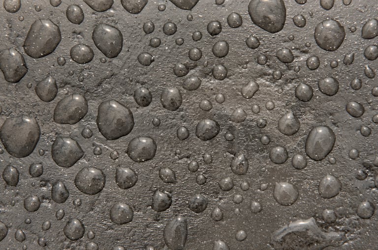 Water droplets beading on smooth sealed concrete surface showing water repelling properties