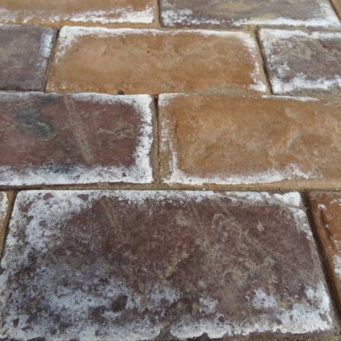 Close-up of frost-covered terracotta clay bricks showing white crystalline ice coating on the surface