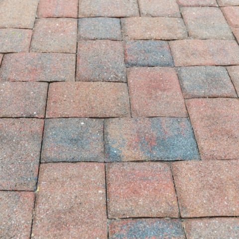 Close-up view of weathered brick pavers laid in a running bond pattern with varying shades of red and gray
